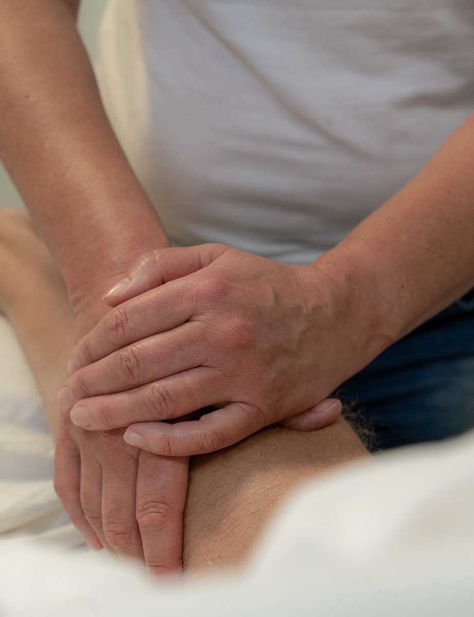 Lillis hænder masserer en lægmuskel på briksen